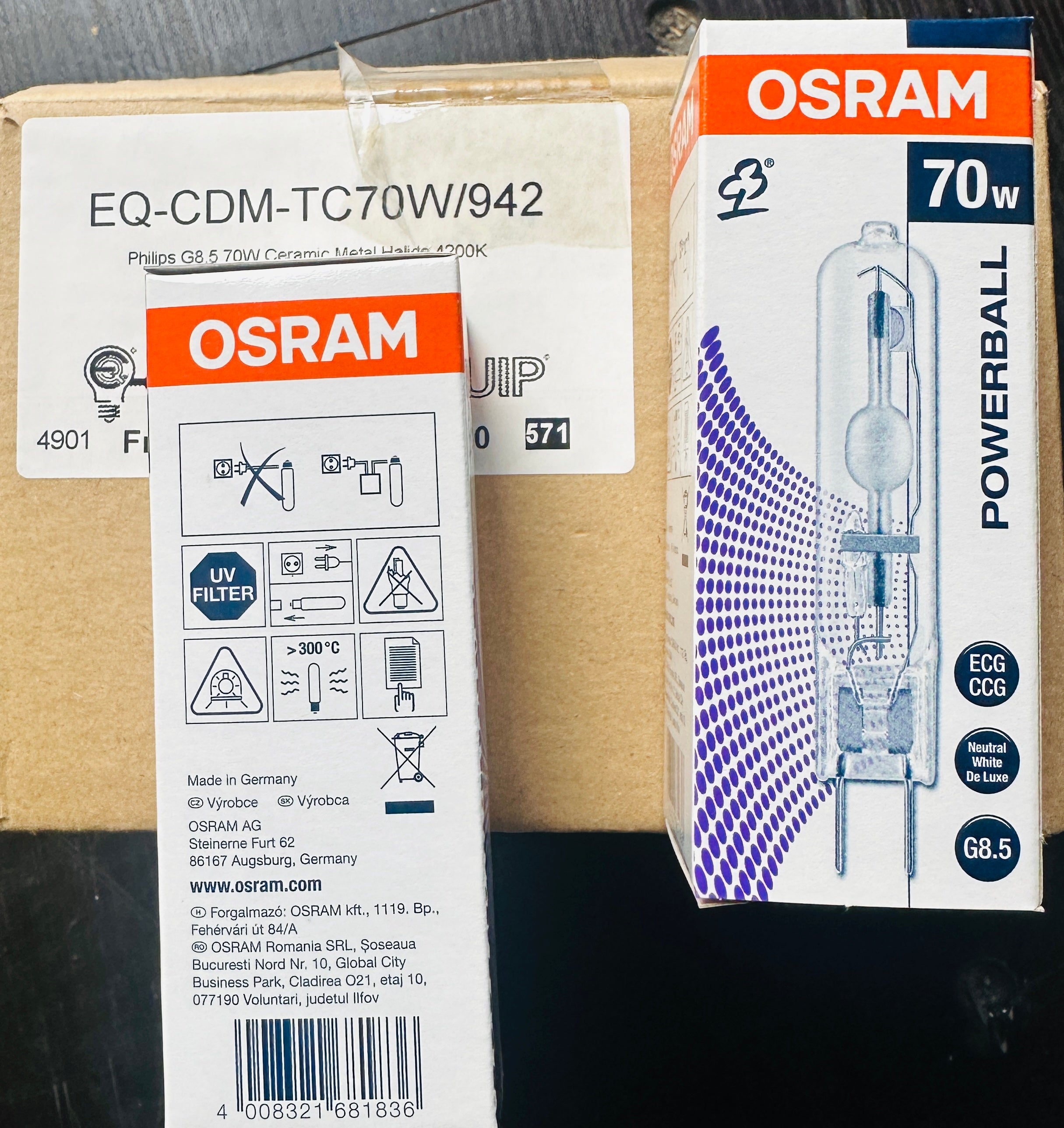 OSRAM Powerball 70W car headlight bulb packaging and the cardboard shipping box, photographed on a dark surface.